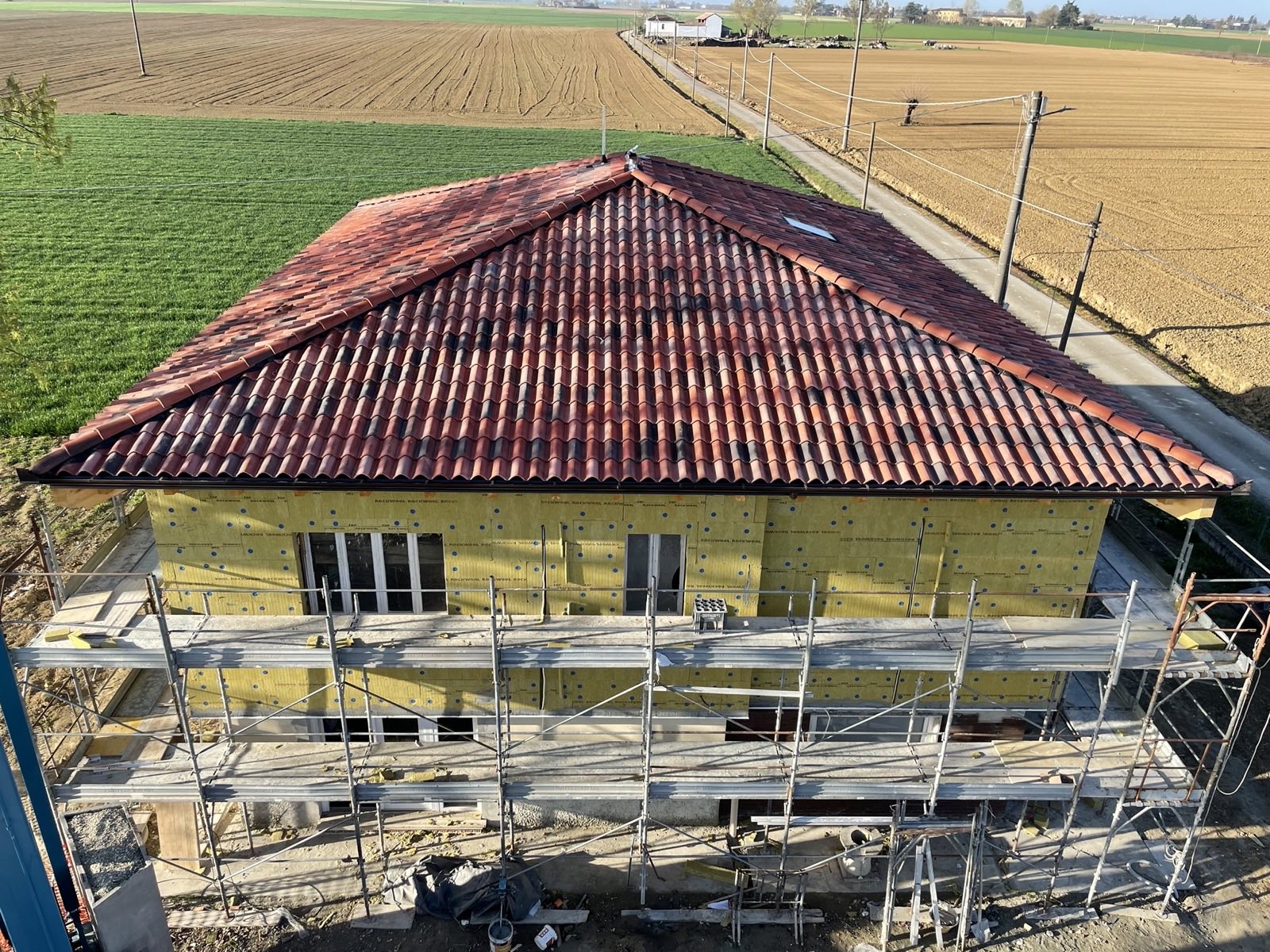 Casa con il cappotto isolante posato sulle pareti e il tetto già rifatto, vista dall'alto con il ponteggio ancora montato