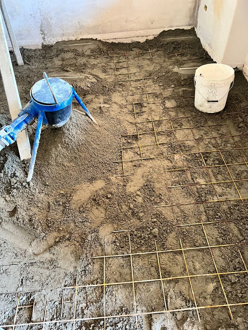 Sottofondo in sabbia e cemento steso in un locale interno, con rete metallica di ripartizione e riferimenti di livello