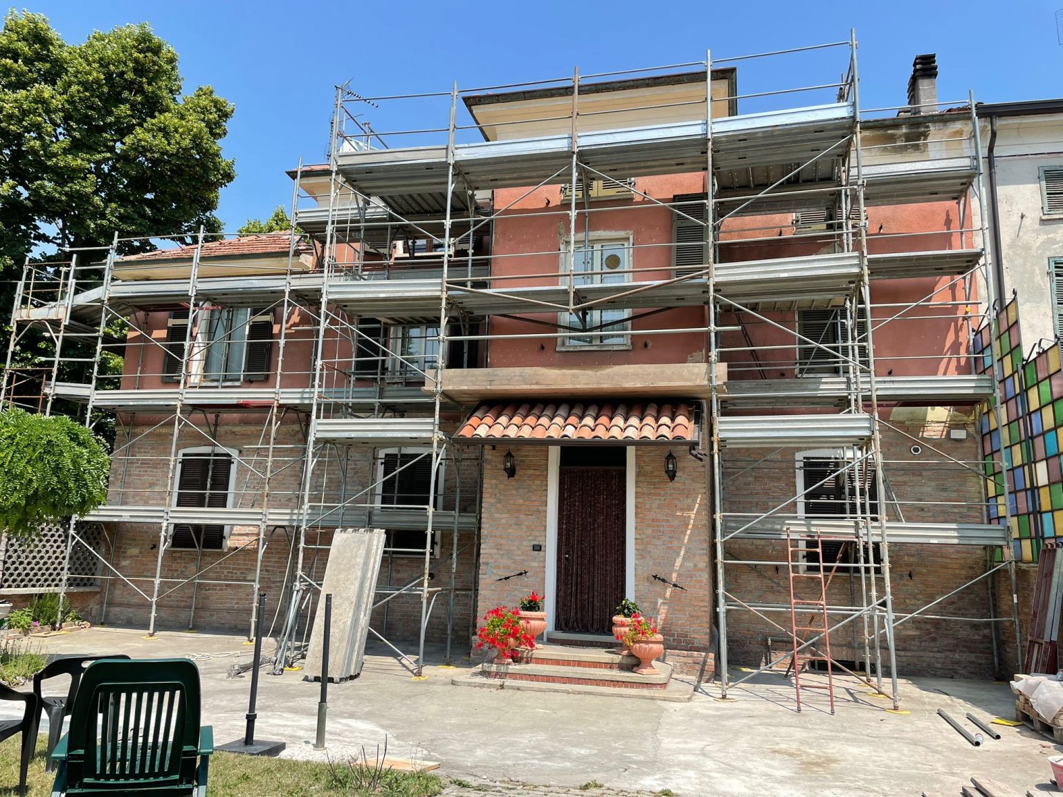 Palazzina d'epoca con ponteggio montato su tutta la facciata, intonaco vecchio e zoccolatura in mattoni a vista